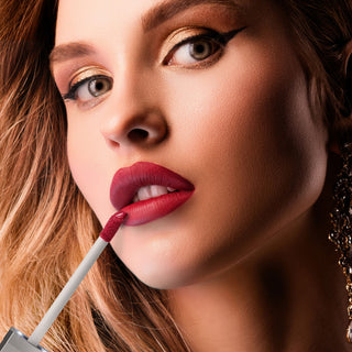 Close-up of model applying Pure Cosmetics Femme Fatale red lip gloss with shimmer gold eyeshadow, showcasing glossy finish and holiday red lip look.