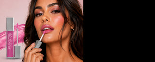 Woman applying soft pink lip gloss with light sparkle with product image and swatch in the background
